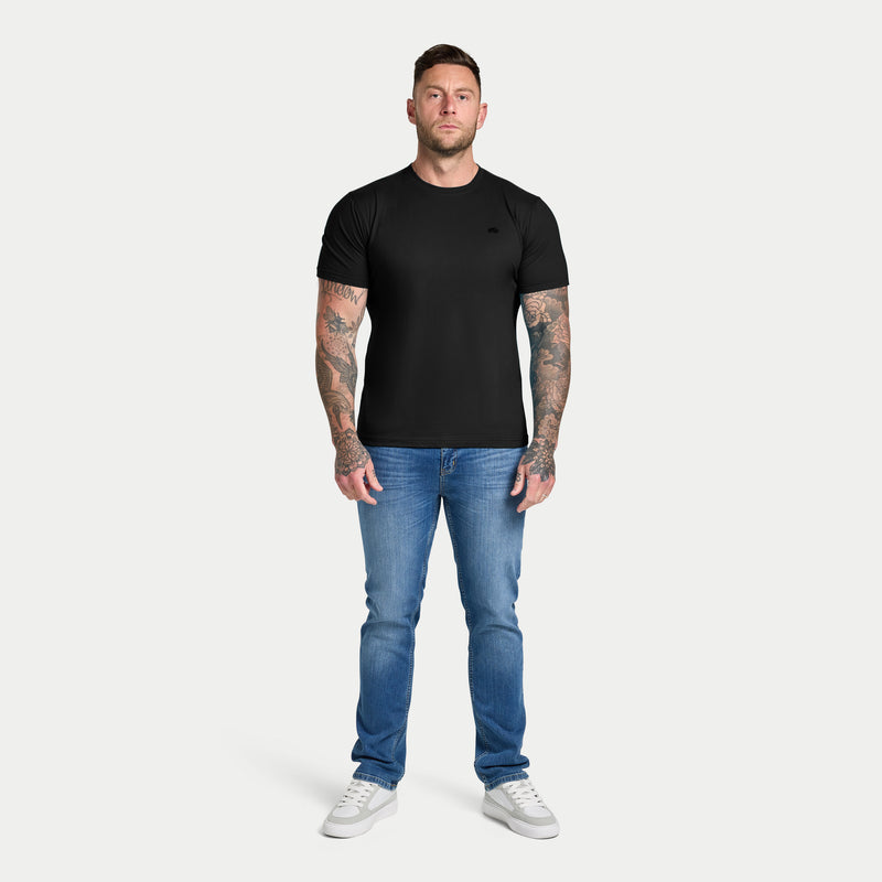 Man wearing a black t-shirt and blue jeans on a white background