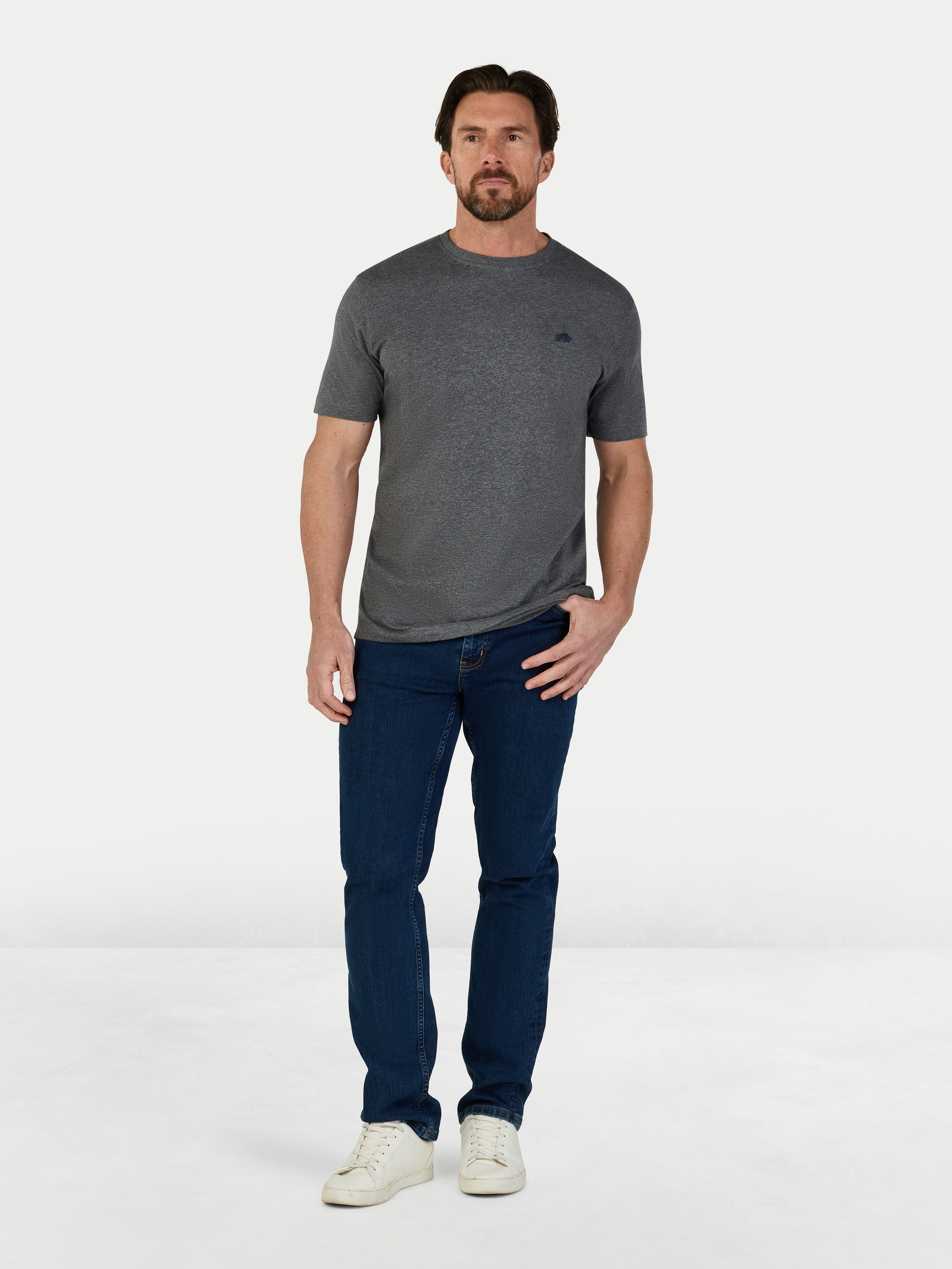 Man wearing a gray t-shirt and blue jeans on a white background