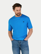 Man wearing a blue t-shirt and jeans on a light gray background
