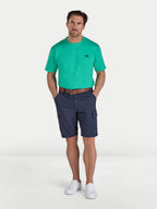 Man wearing a green t-shirt and navy shorts on a white background