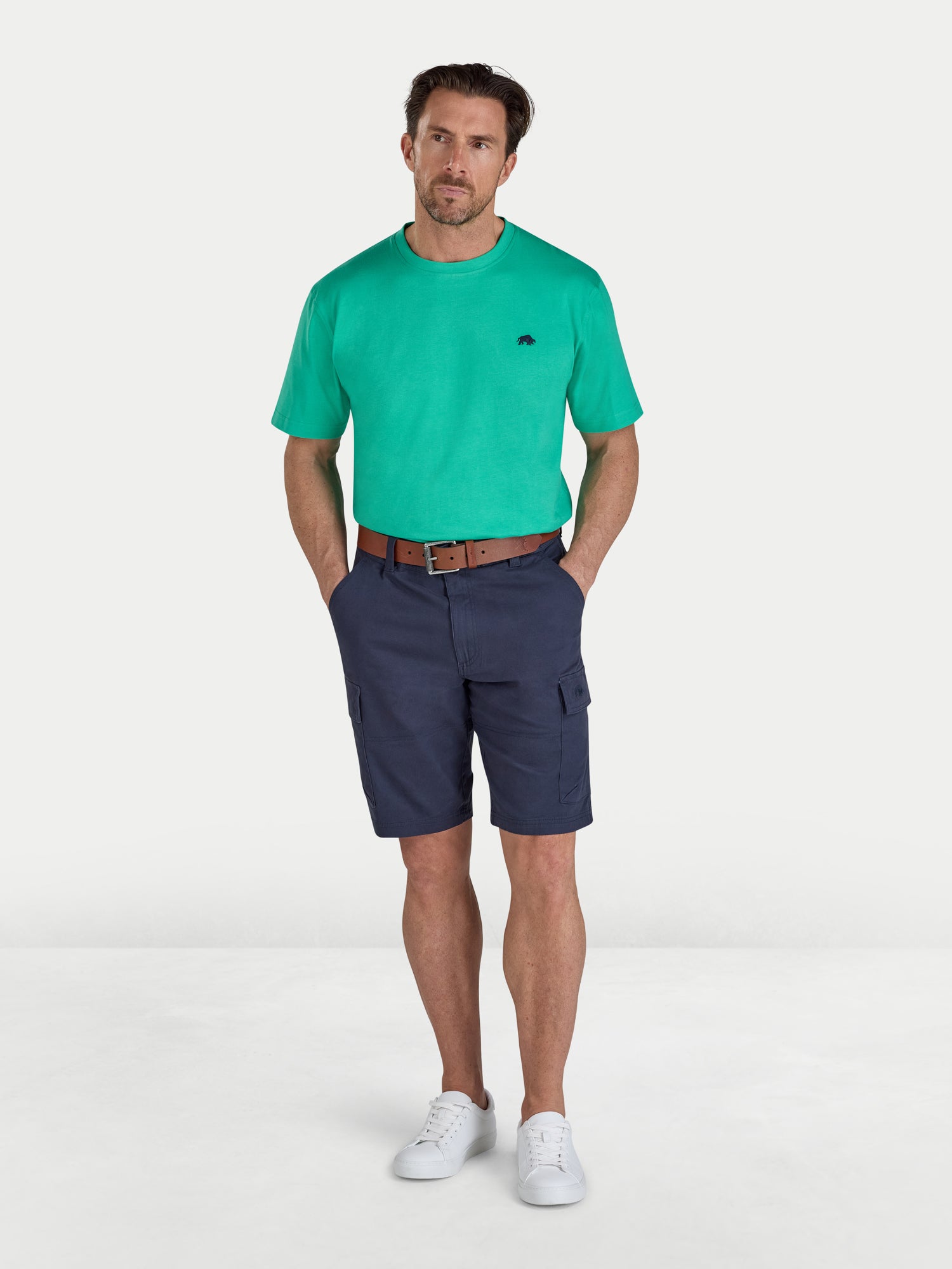 Man wearing a green t-shirt and navy shorts on a white background