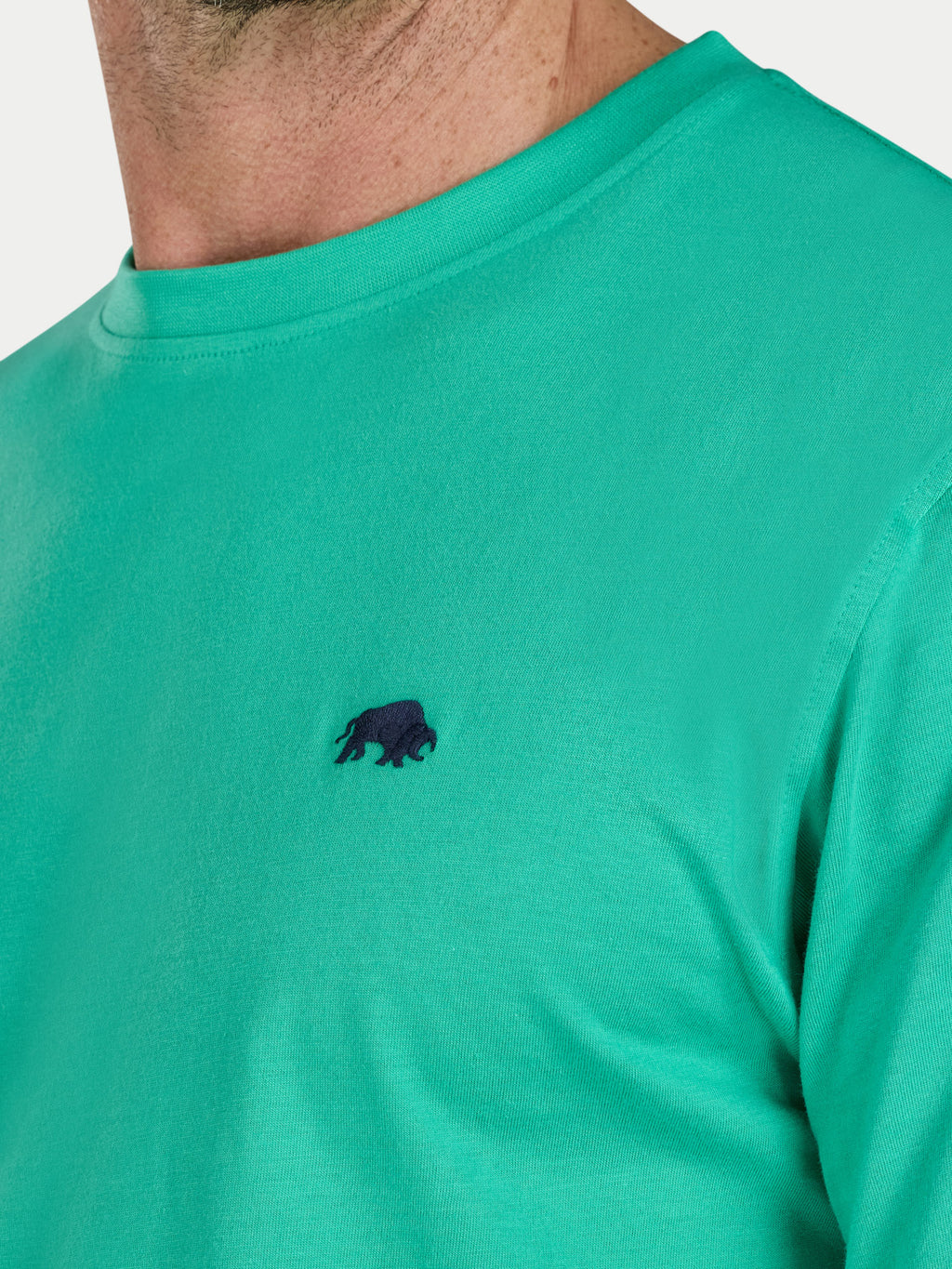 Green t-shirt with a small black logo on a white background