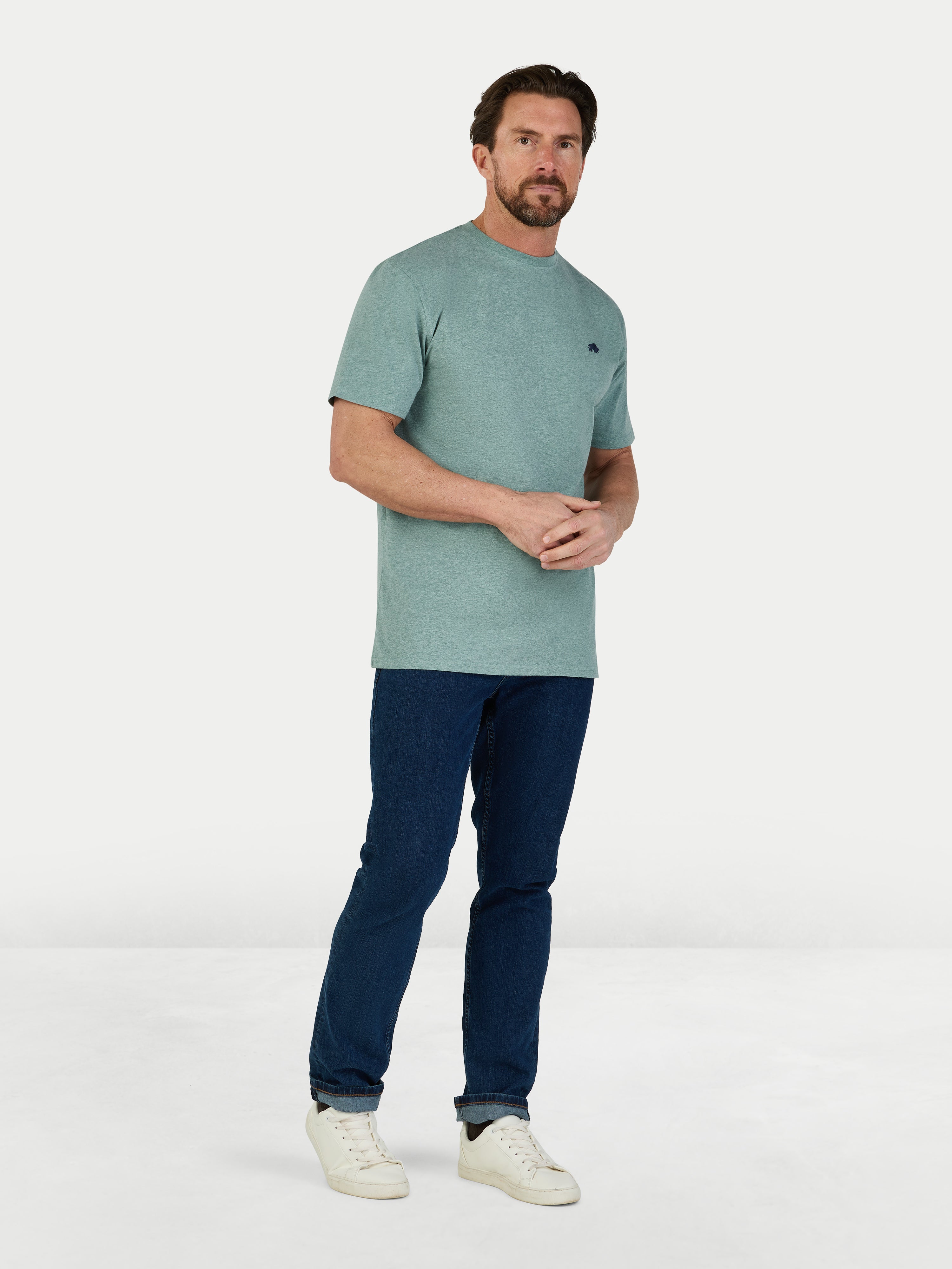 Man wearing a green t-shirt and blue pants on a white background