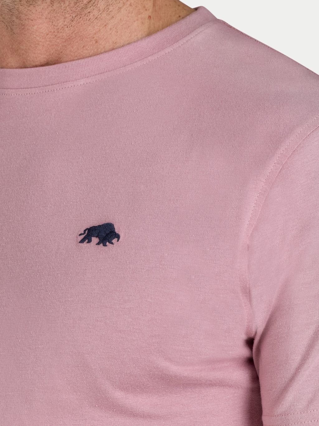 Close-up of a pink t-shirt with a black logo on a light gray background