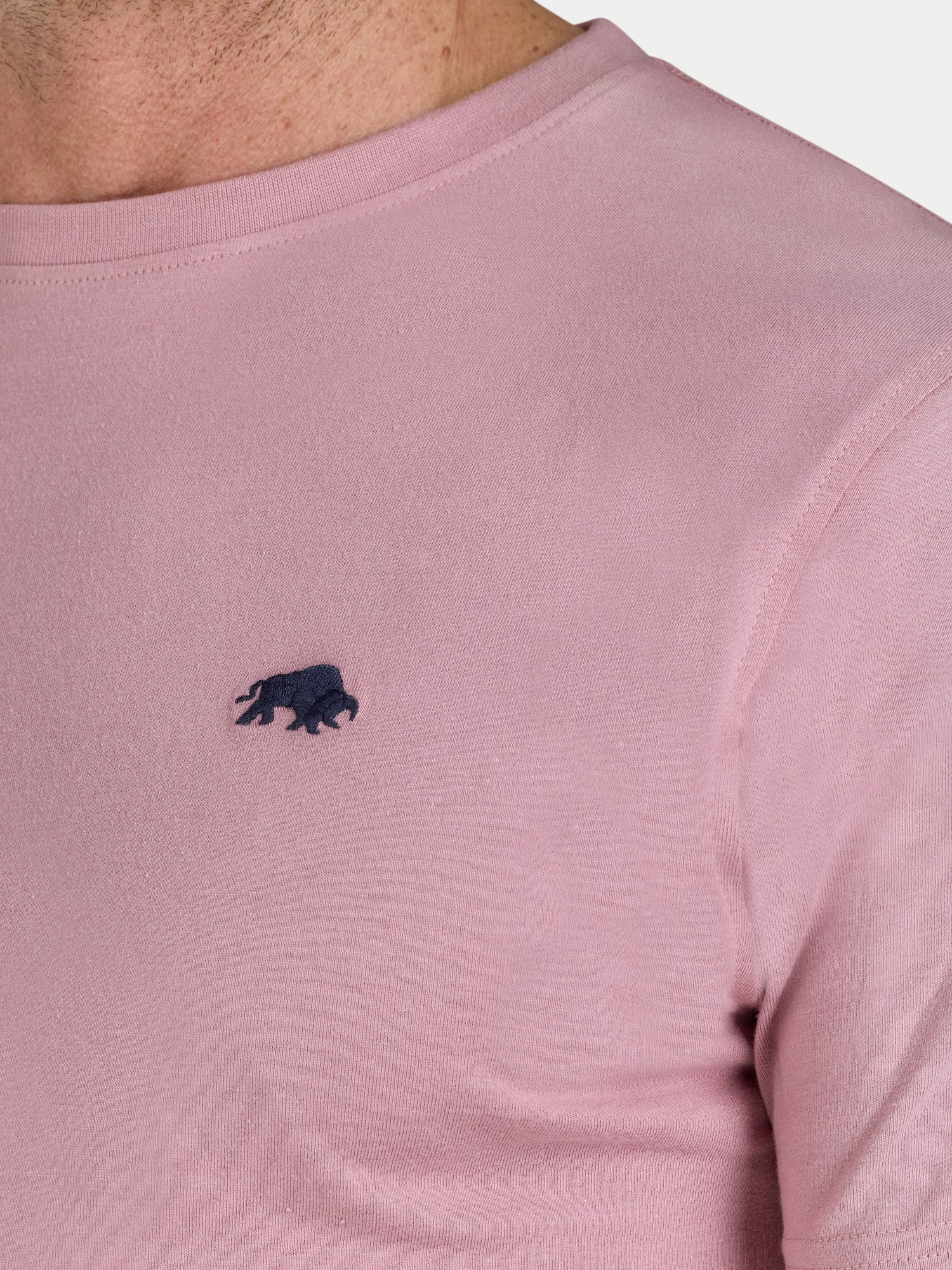 Close-up of a pink t-shirt with a black logo on a light gray background