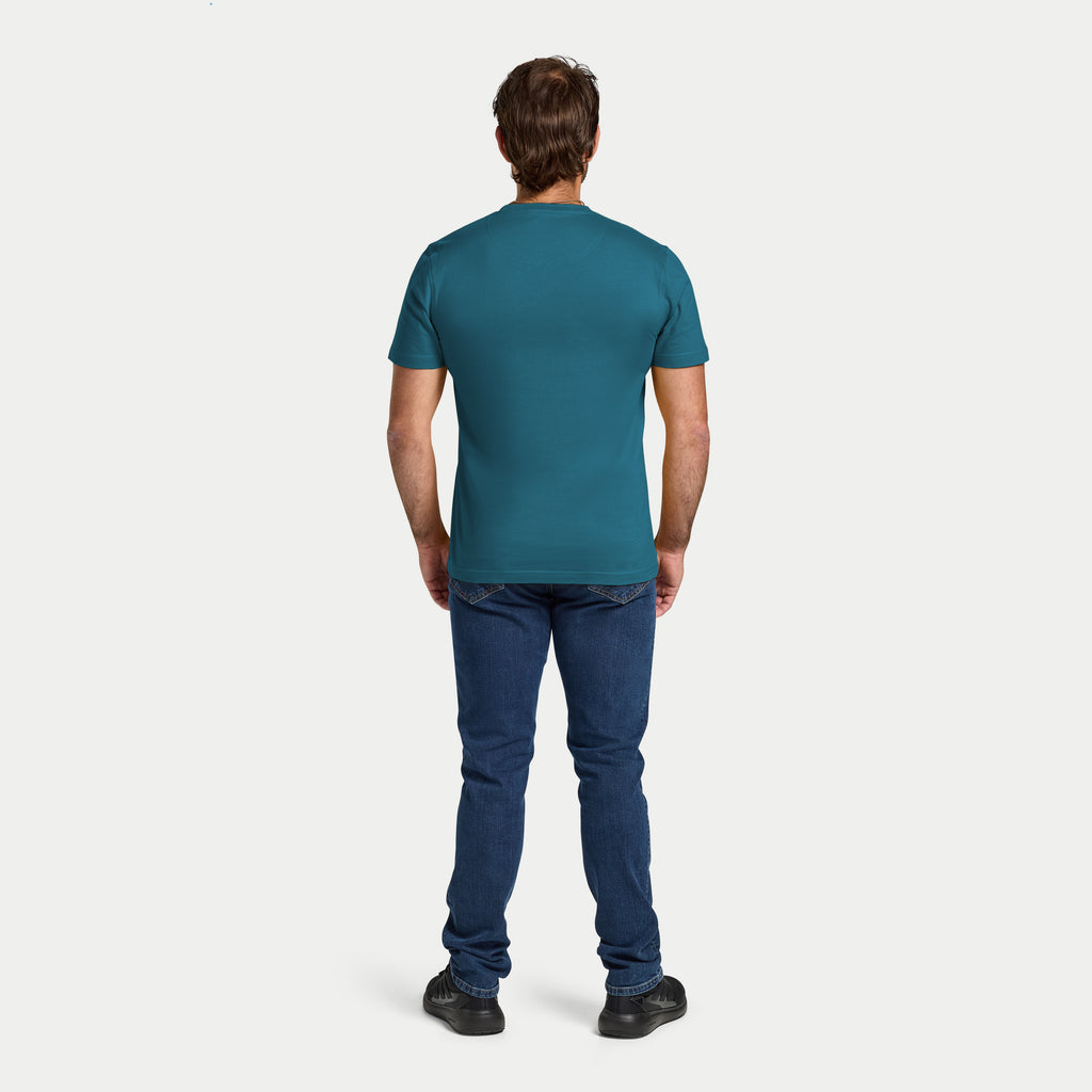 Man wearing a teal t-shirt and blue jeans on a white background