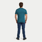 Man wearing a teal t-shirt and blue jeans on a white background