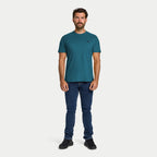 Man wearing a teal t-shirt and blue jeans on a white background