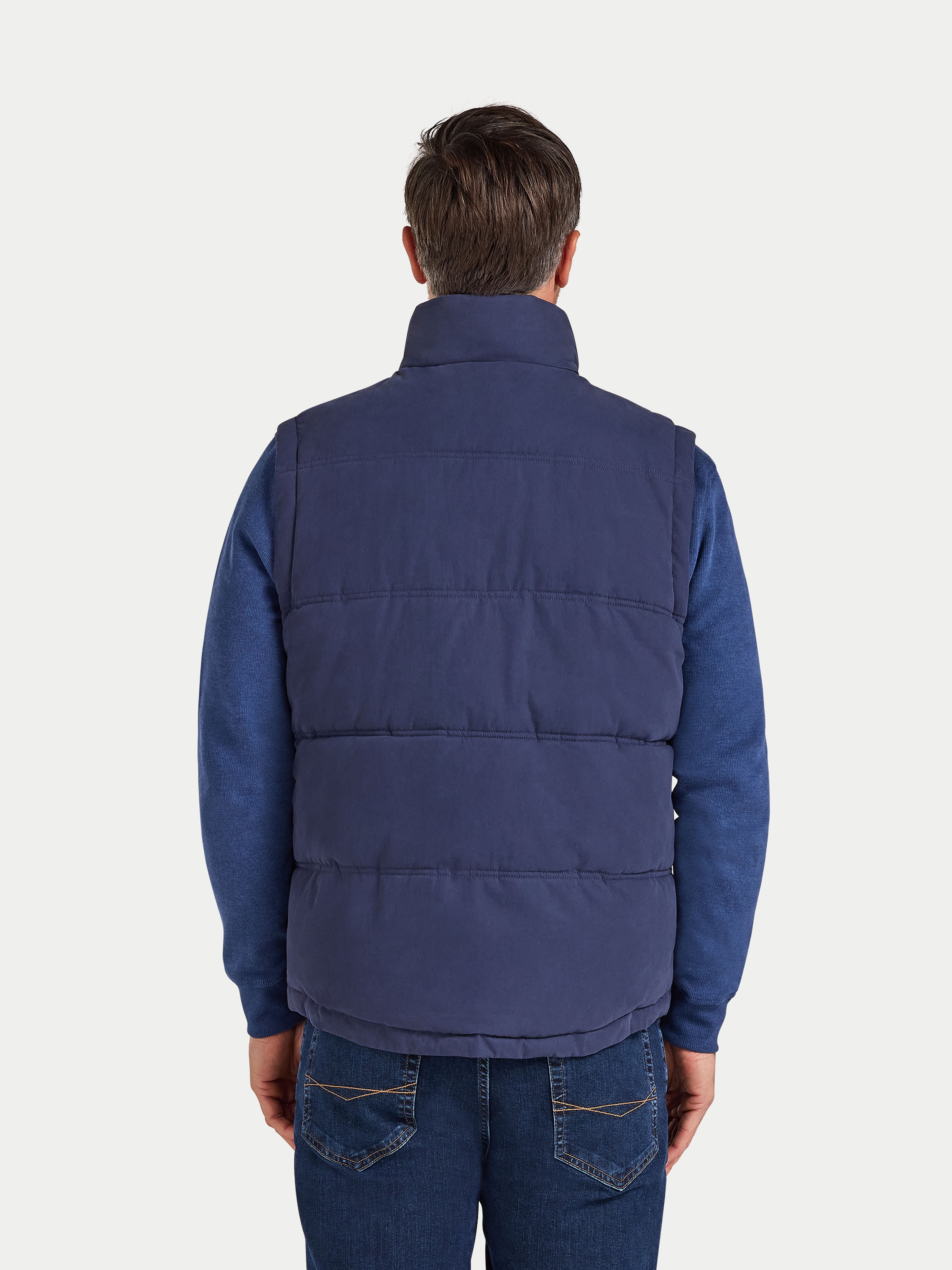 Man wearing a blue puffer vest on a white background