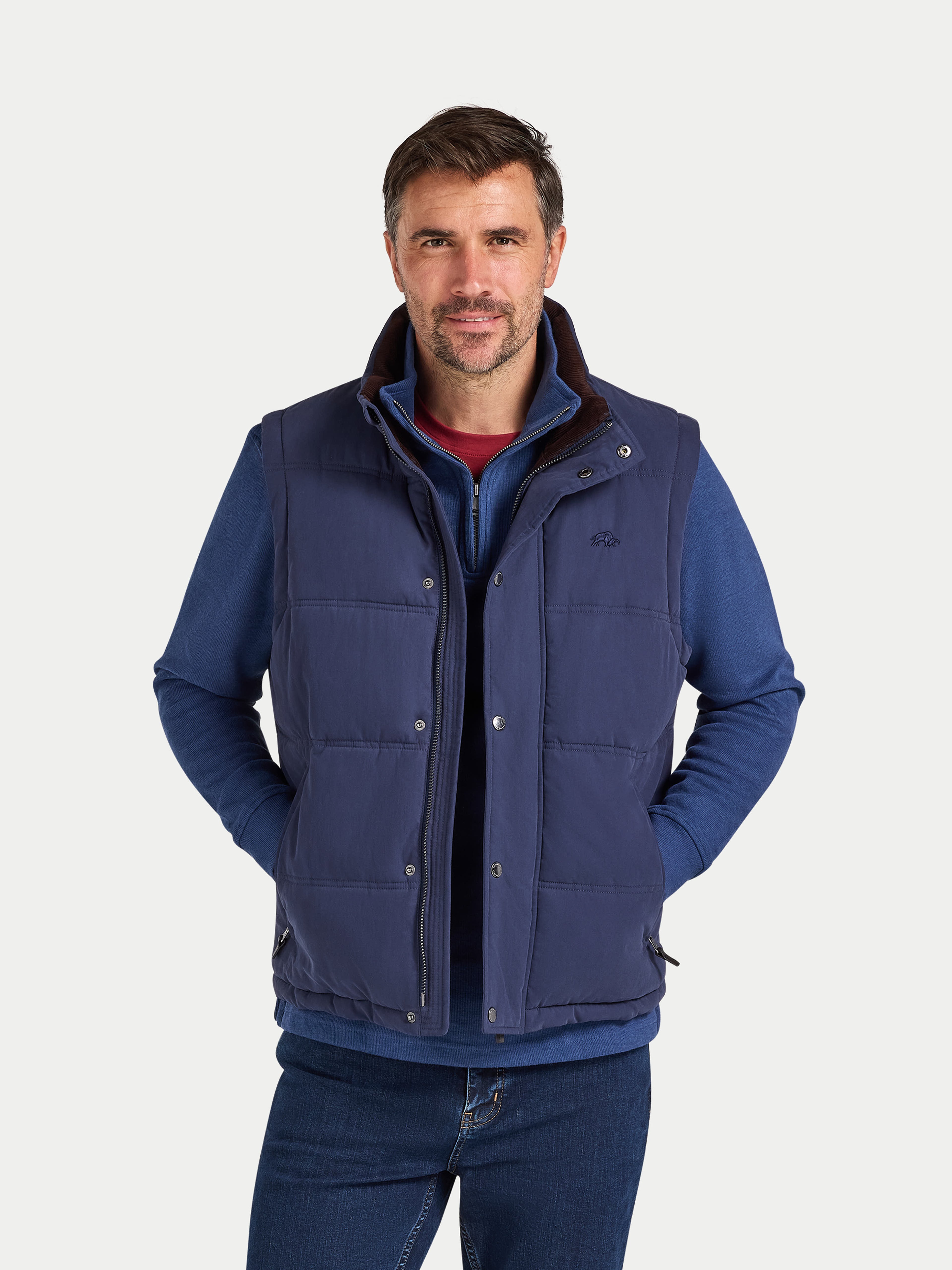 Man wearing a blue quilted vest on a white background