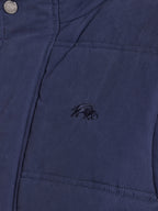 Close-up of a blue jacket with an embroidered logo on the chest pocket.