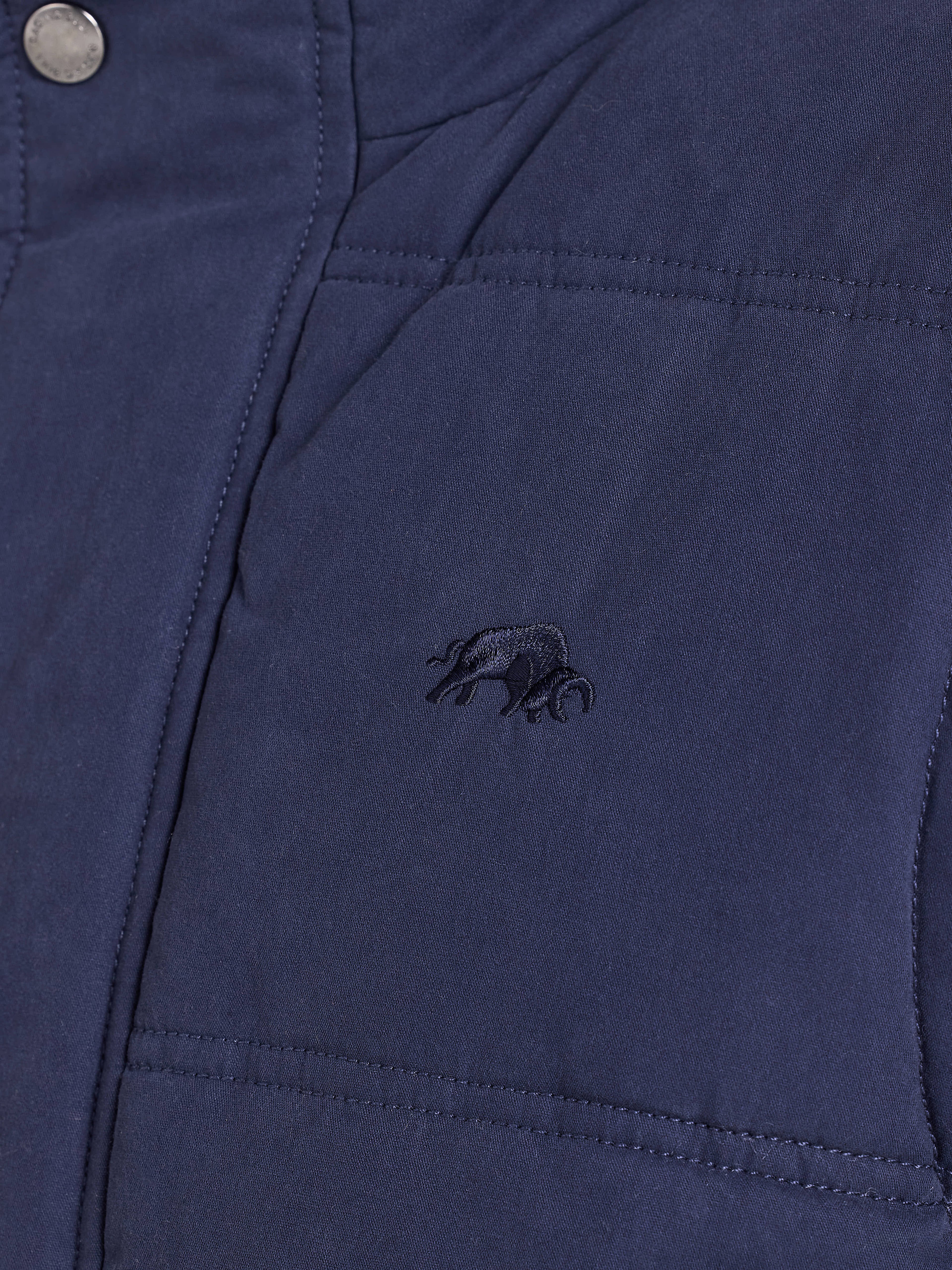 Close-up of a blue jacket with an embroidered logo on the chest pocket.