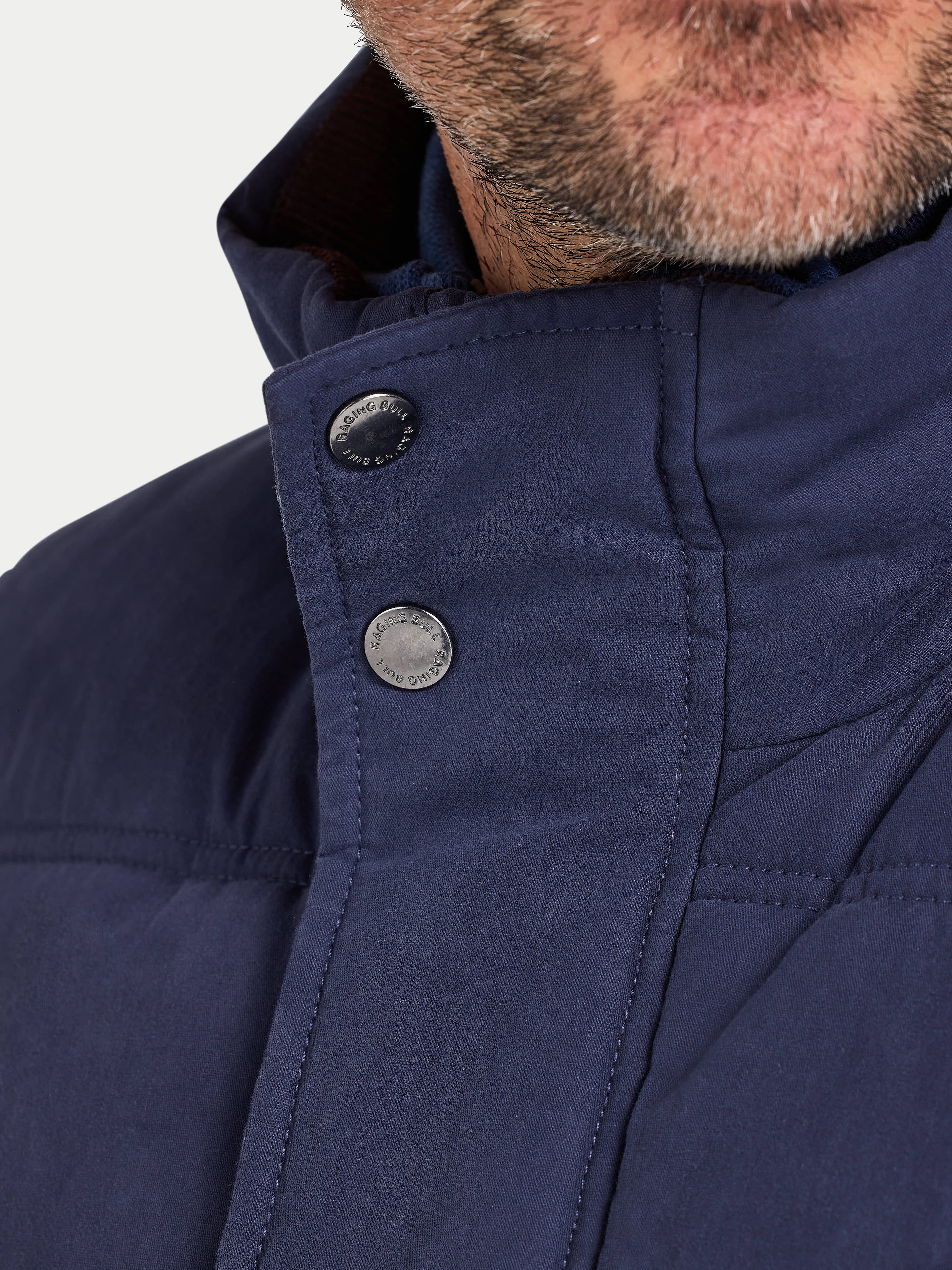Close-up of a navy blue jacket with buttons on a light gray background