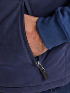 Close-up of a person wearing a navy blue jacket with a zipper, showing a hand in the pocket.