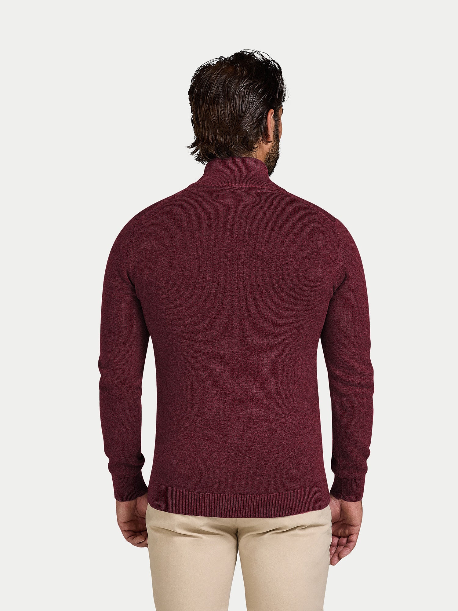 Man wearing a burgundy sweater and beige pants on a white background
