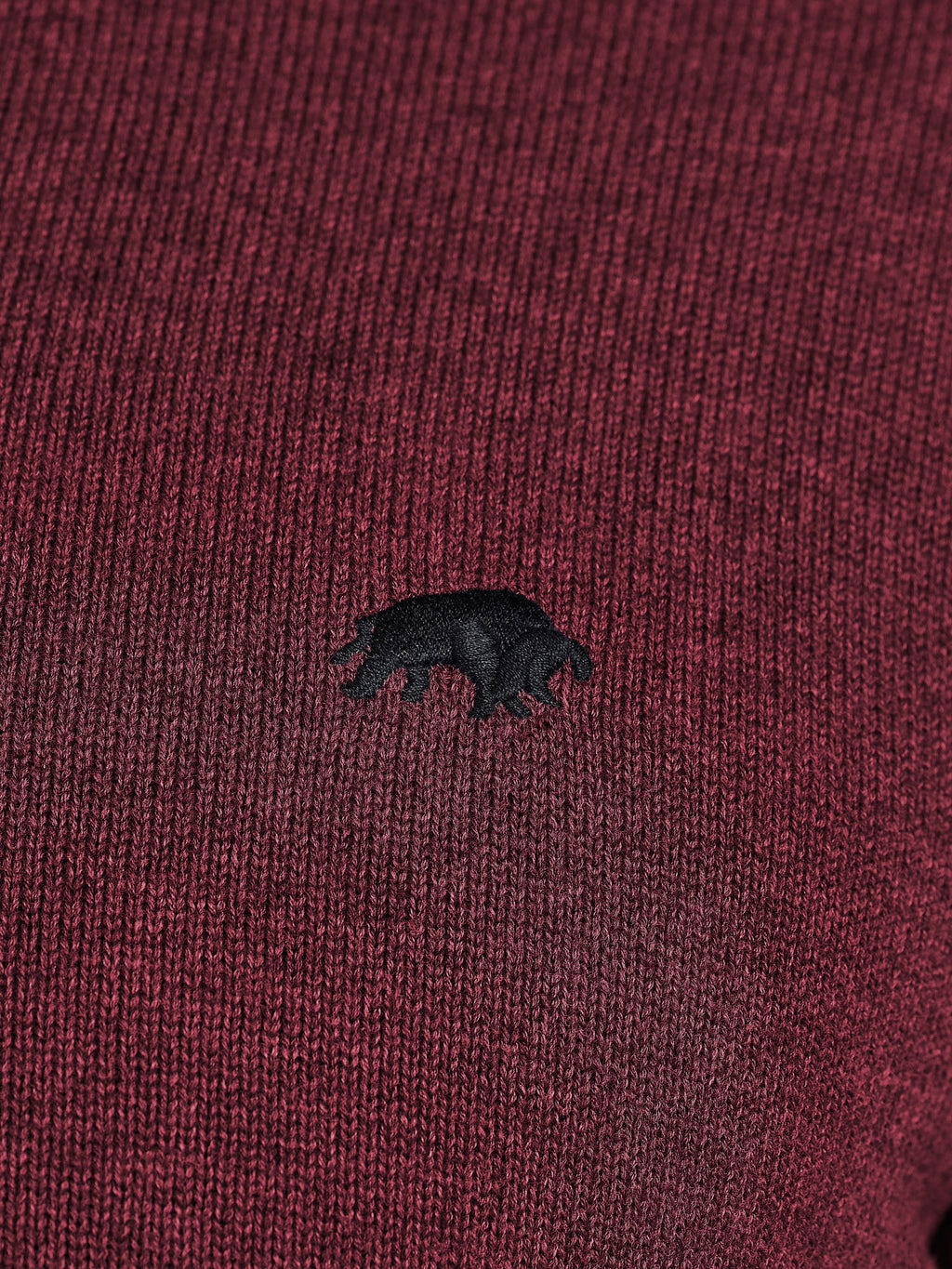 Close-up of a maroon fabric with a black bear emblem.