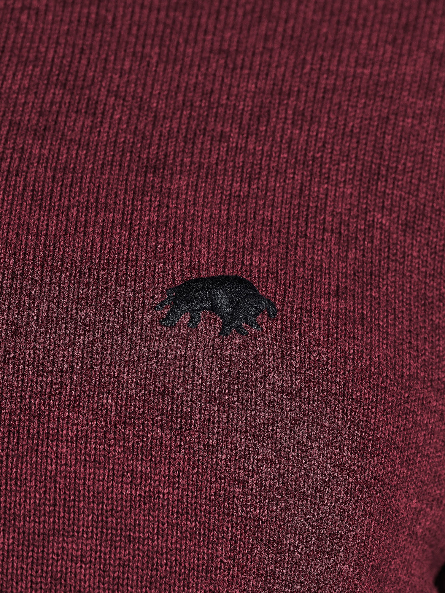 Close-up of a maroon fabric with a black bear emblem.