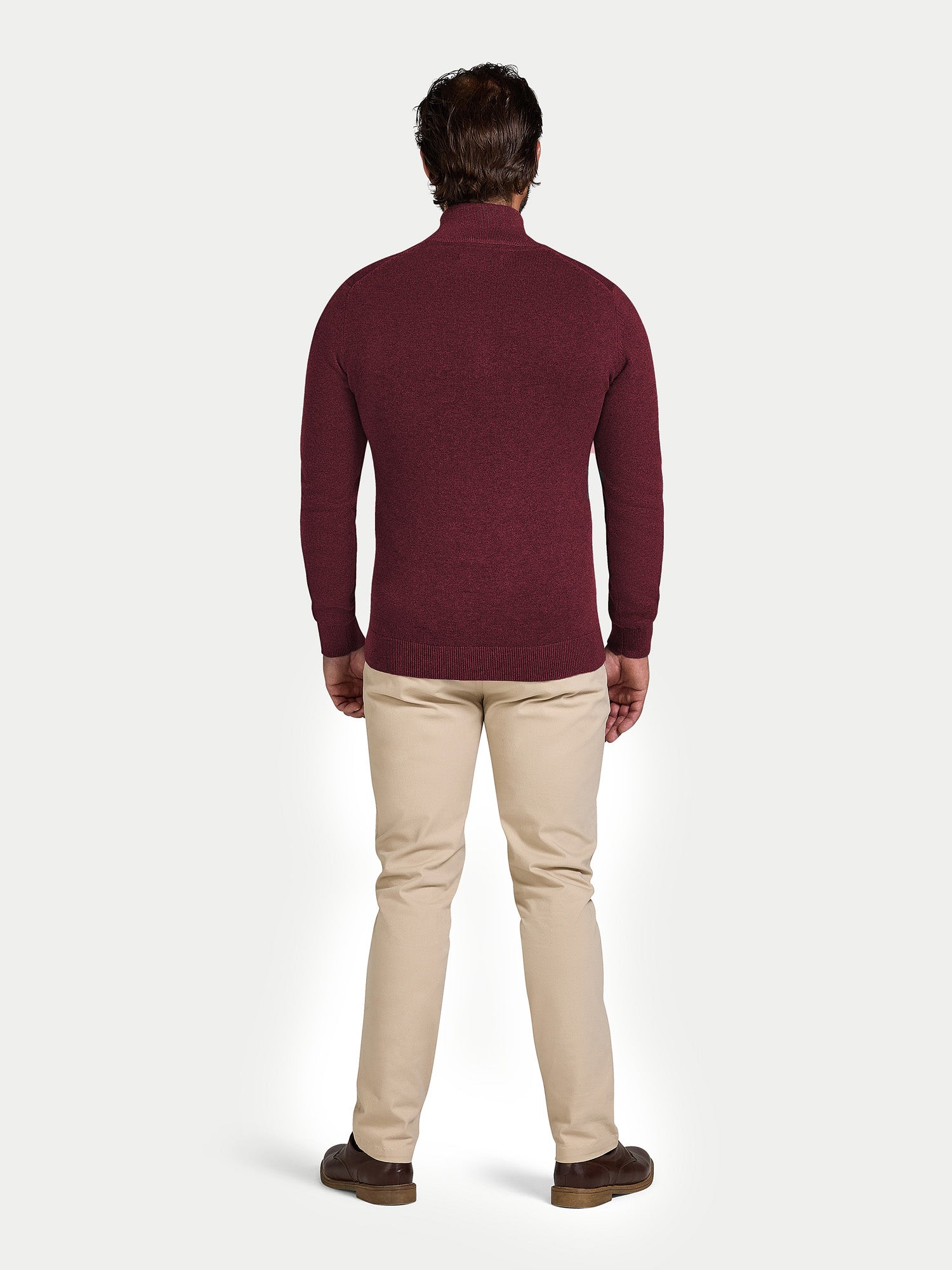 Man wearing a burgundy sweater and beige pants on a white background