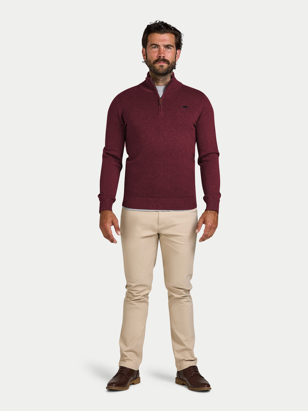 Man wearing a burgundy sweater and beige pants on a white background
