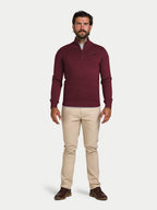 Man wearing a burgundy sweater and beige pants on a white background