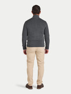 Man wearing a gray sweater and beige pants on a white background