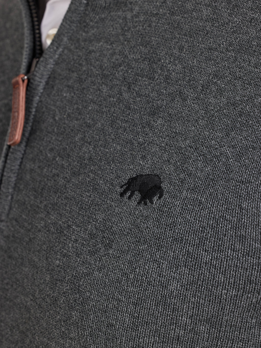 Close-up of a dark gray knit jumper with a small Raging Bull emblem.