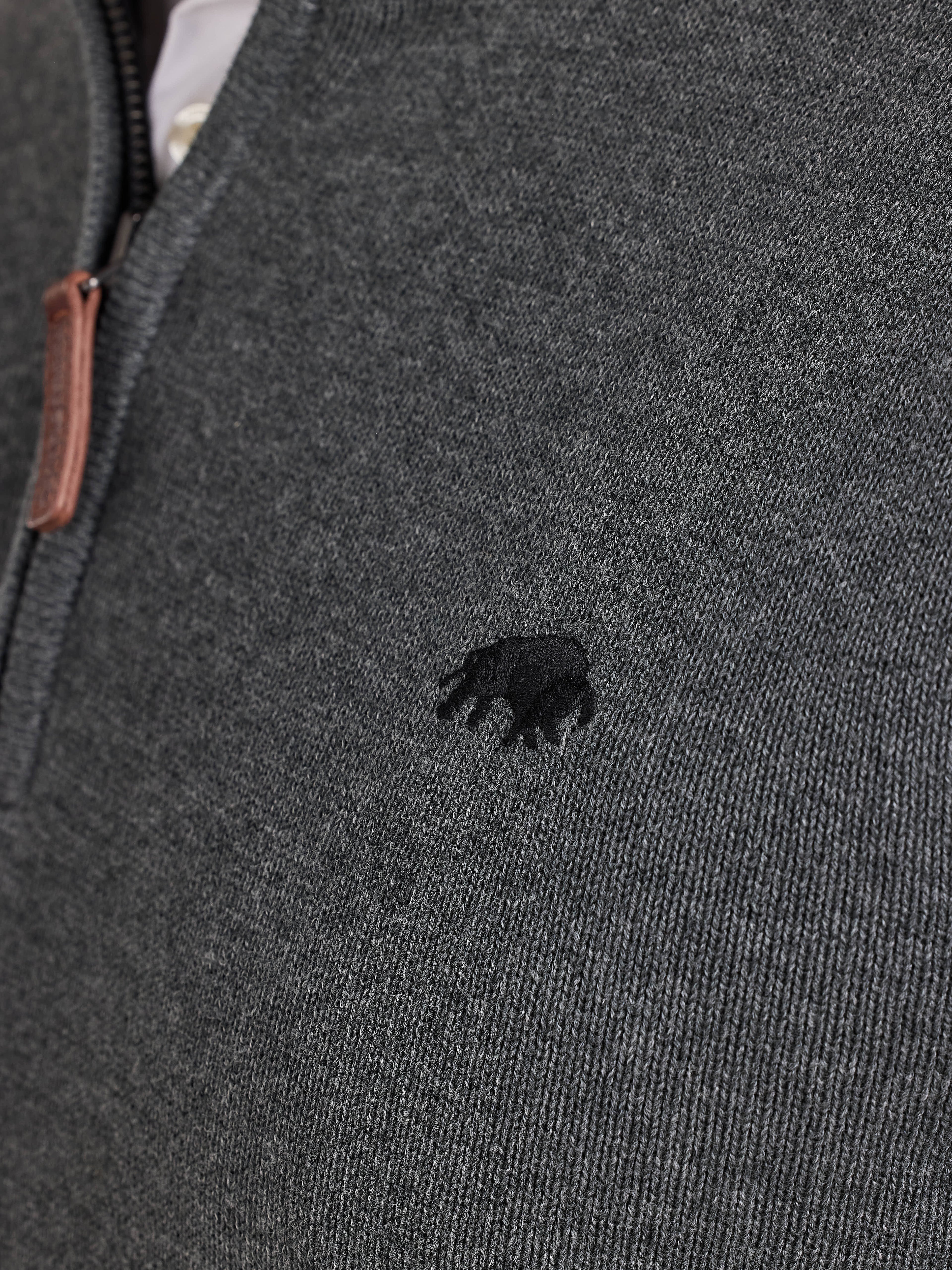 Close-up of a dark gray knit jumper with a small Raging Bull emblem.