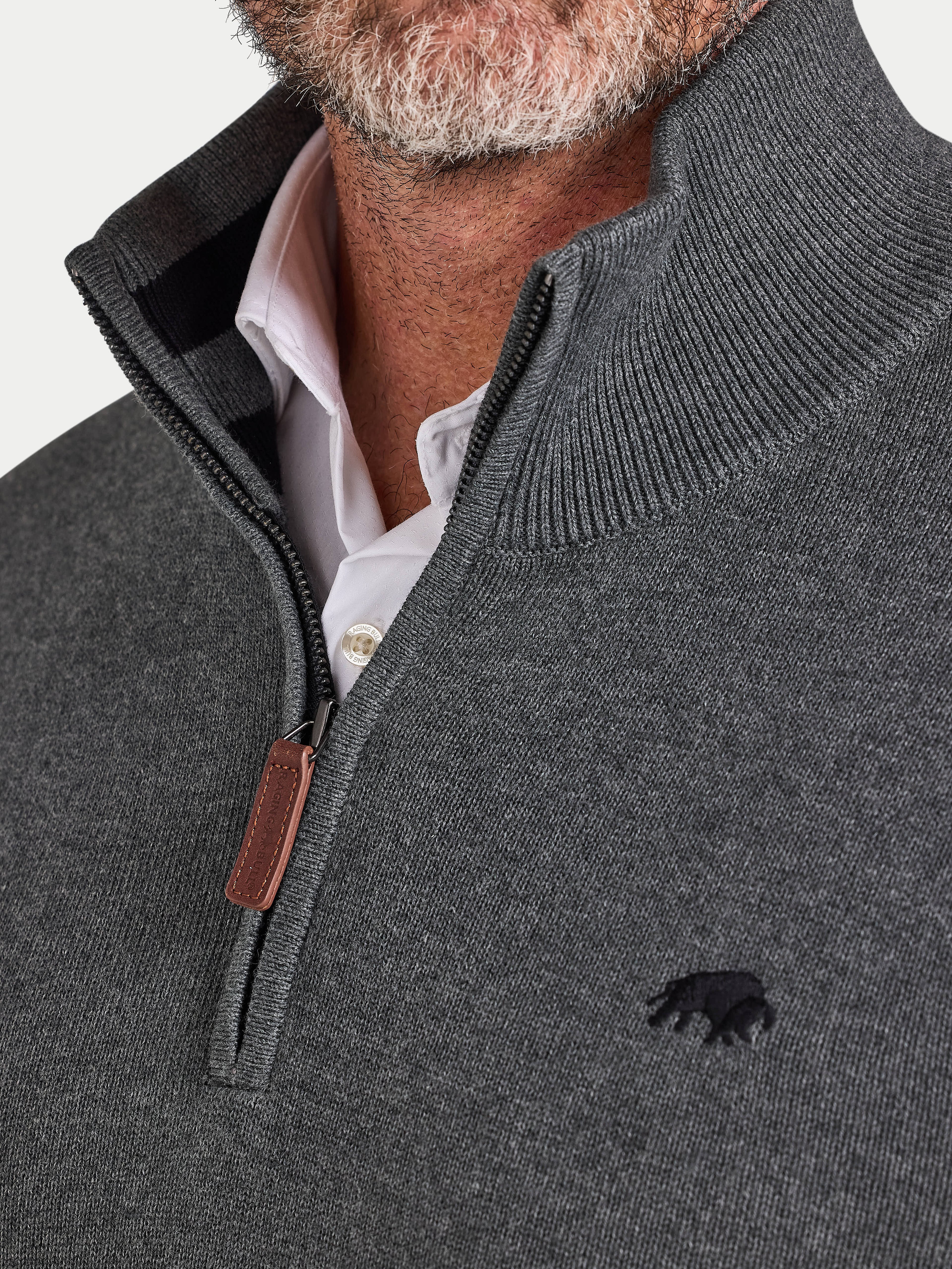Close-up of a man wearing a gray half-zip sweater with a logo on a light gray background