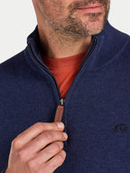 Man wearing a navy blue zip-up sweater over a red shirt with a visible brand logo.