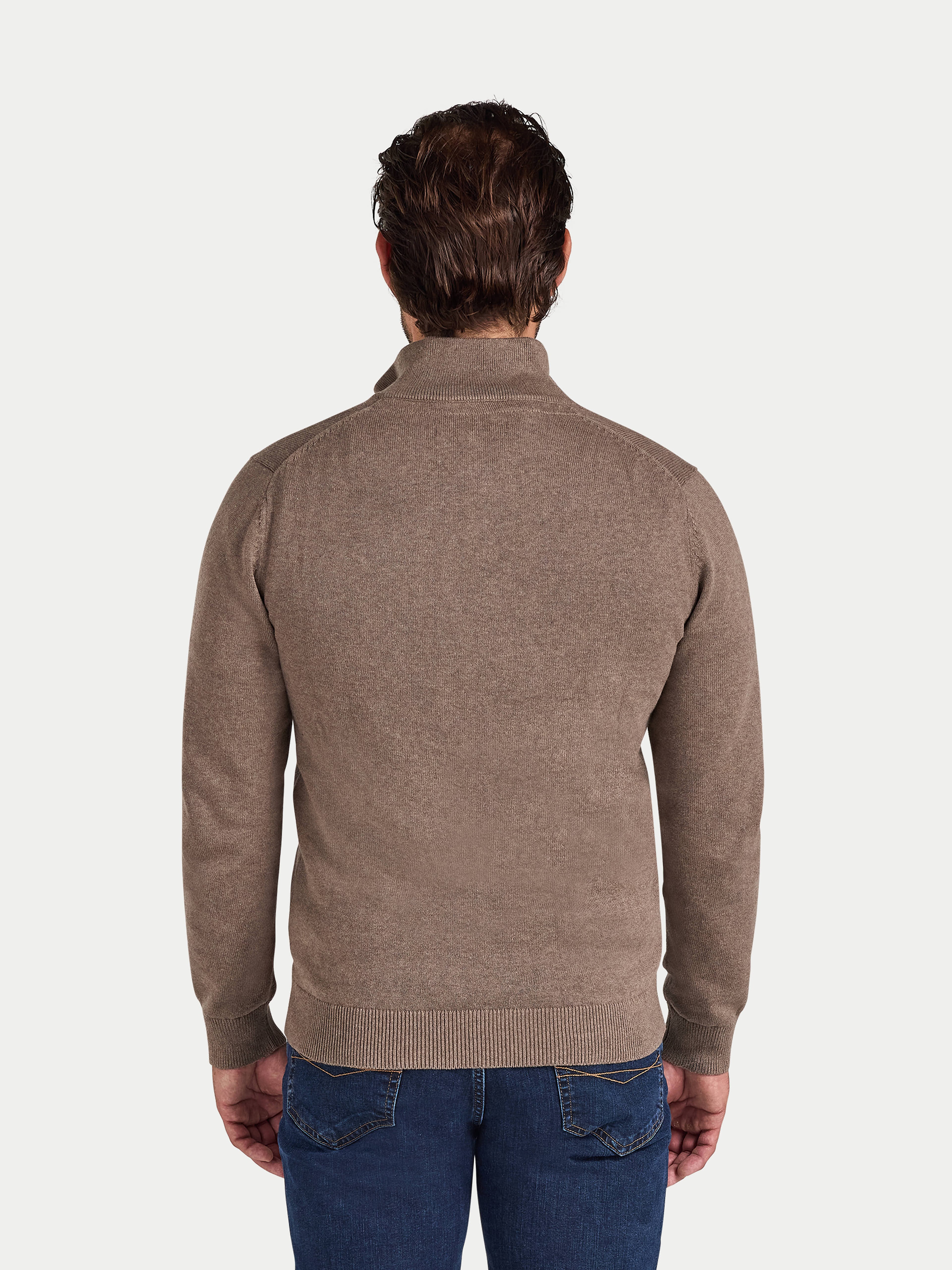 Man wearing a brown sweater and blue jeans on a white background