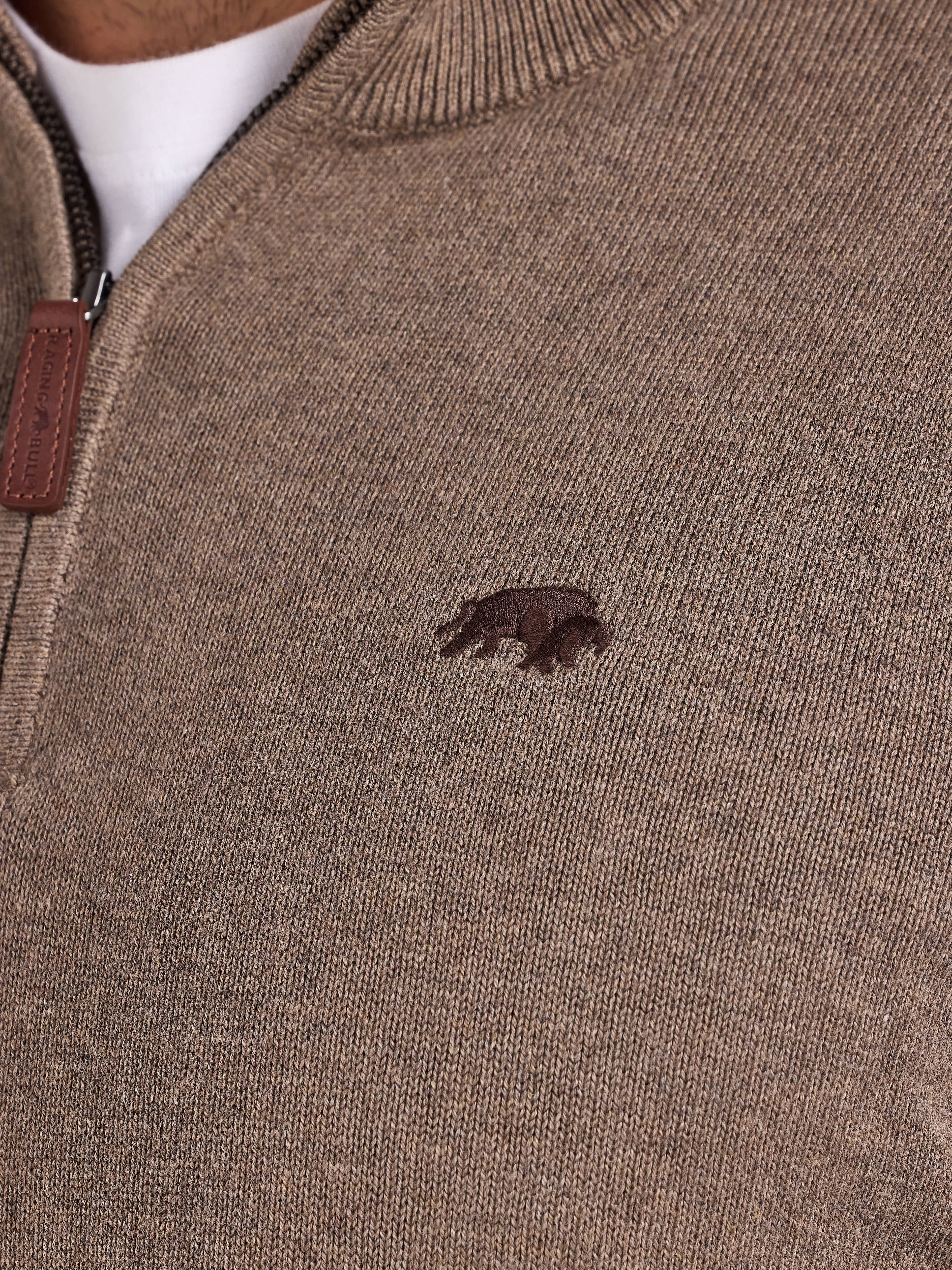 Close-up of a brown sweater with a small logo on the chest.