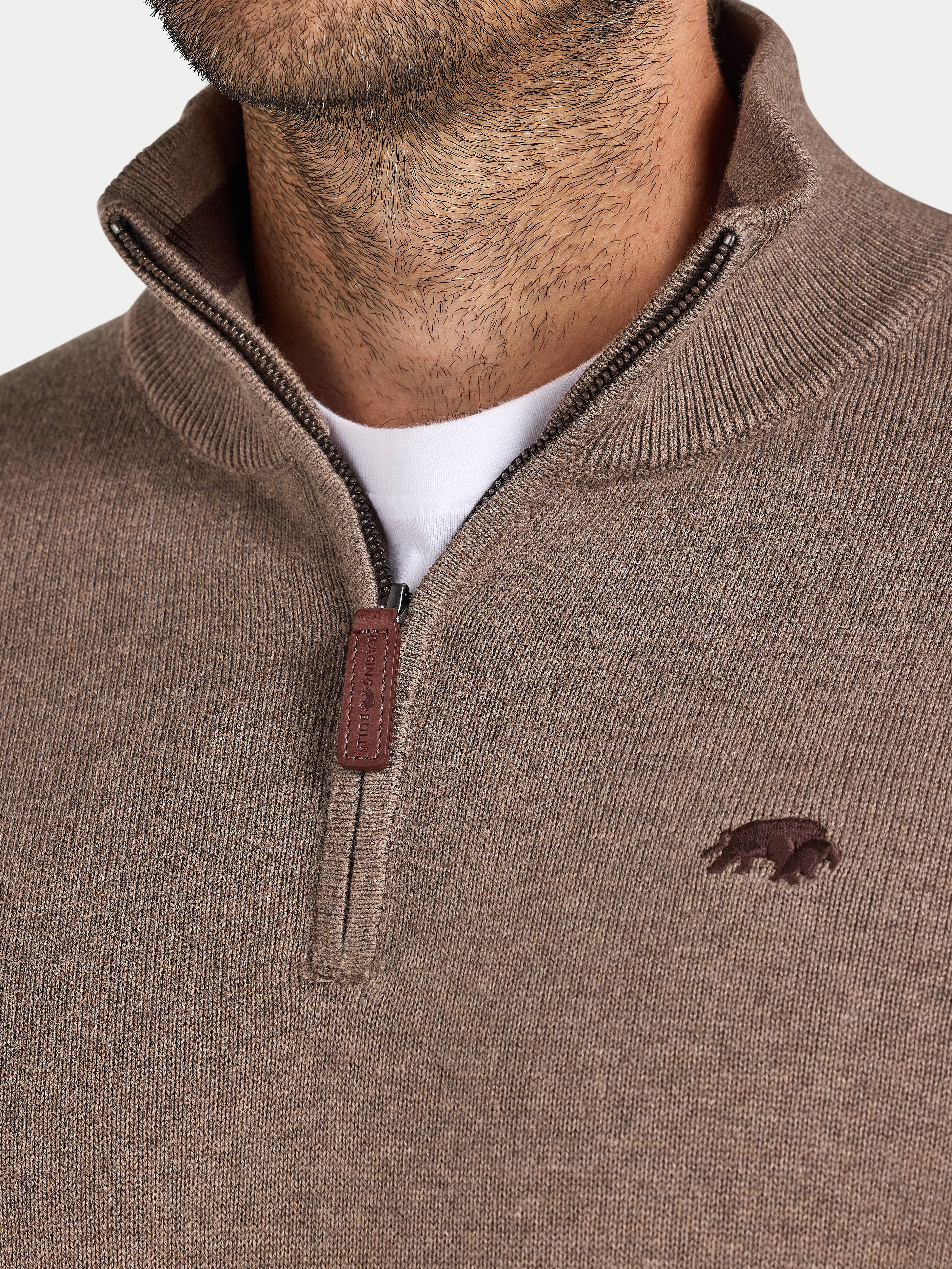 Brown sweater with a zipper and logo on a neutral background