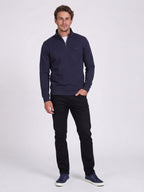 Man wearing a navy blue sweater and black trousers on a white background