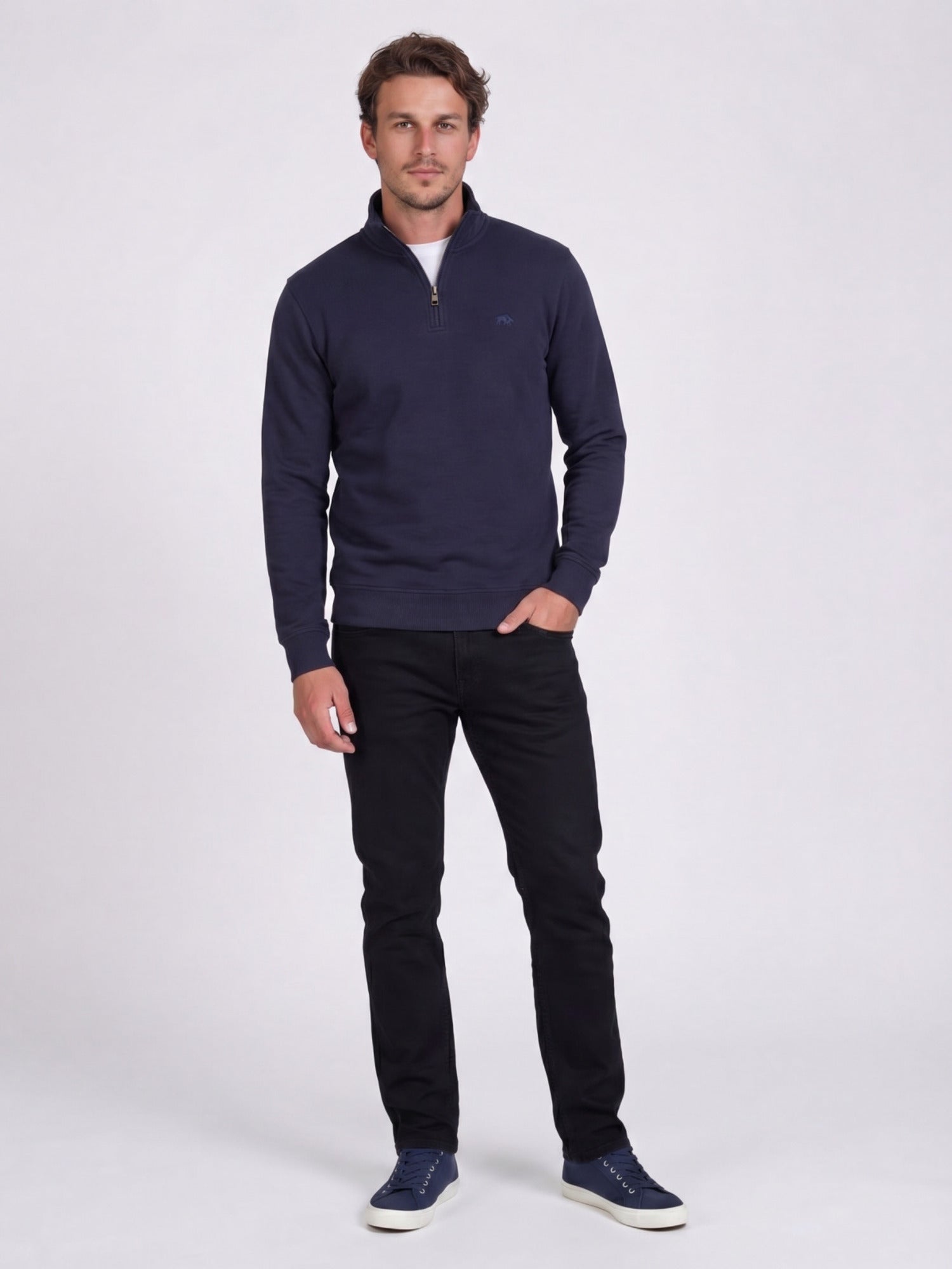 Man wearing a navy blue sweater and black trousers on a white background