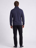 Man wearing a navy blue sweater and black trousers on a white background