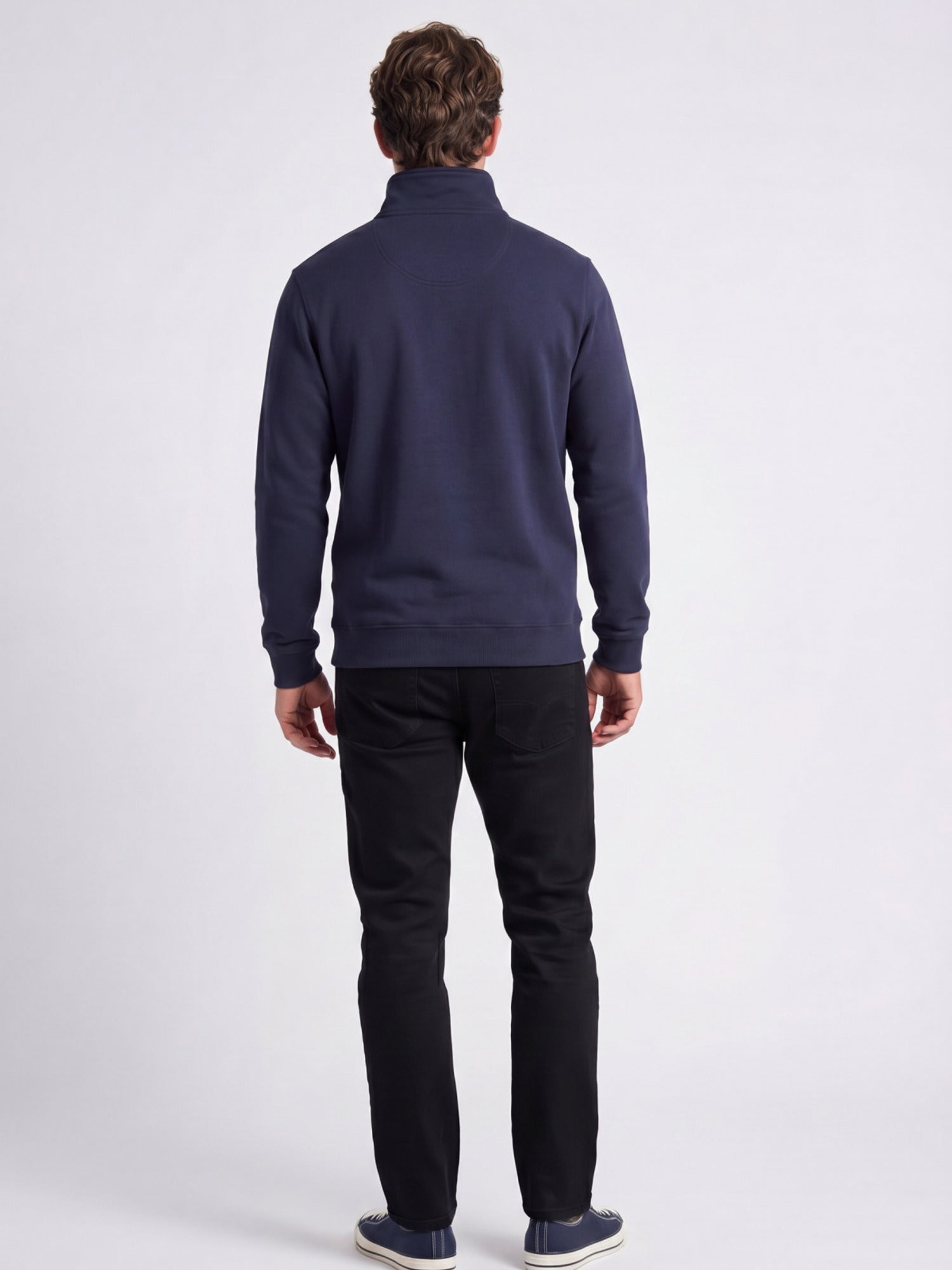 Man wearing a navy blue sweater and black trousers on a white background