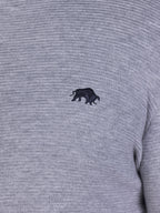 Close-up image of black Raging Bull logo on grey sweater.