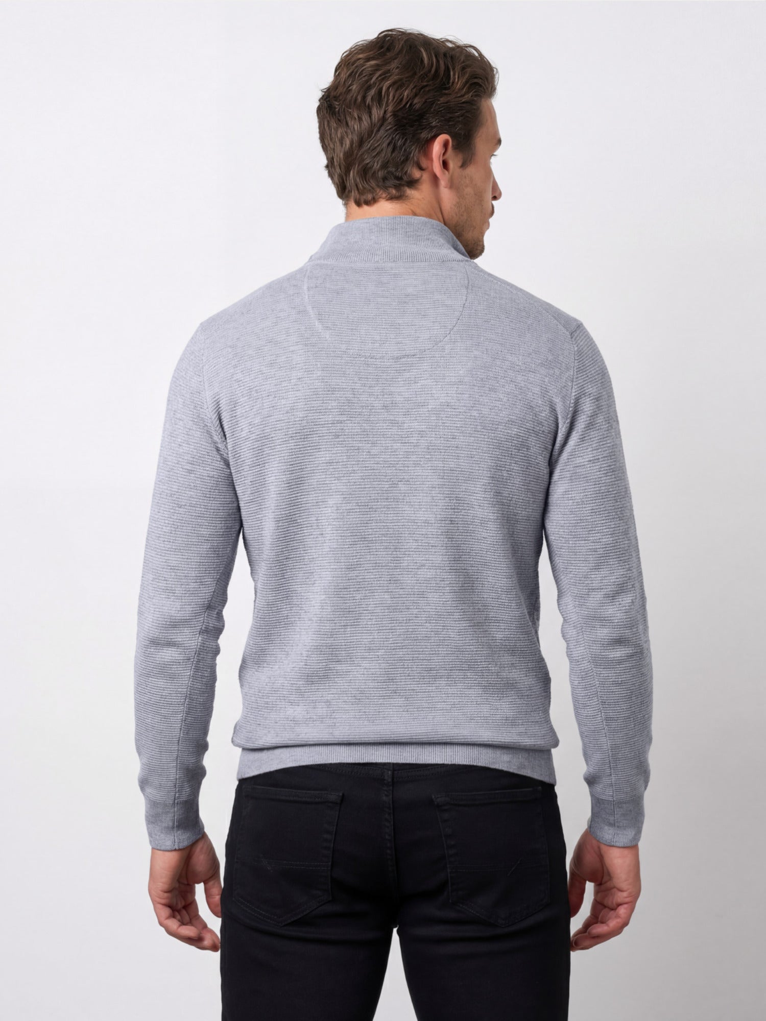 Man wearing a gray sweater and black pants on a white background