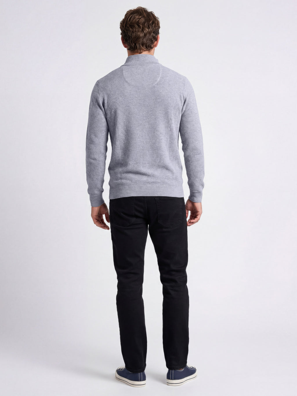Man wearing a gray sweater and black trousers on a white background