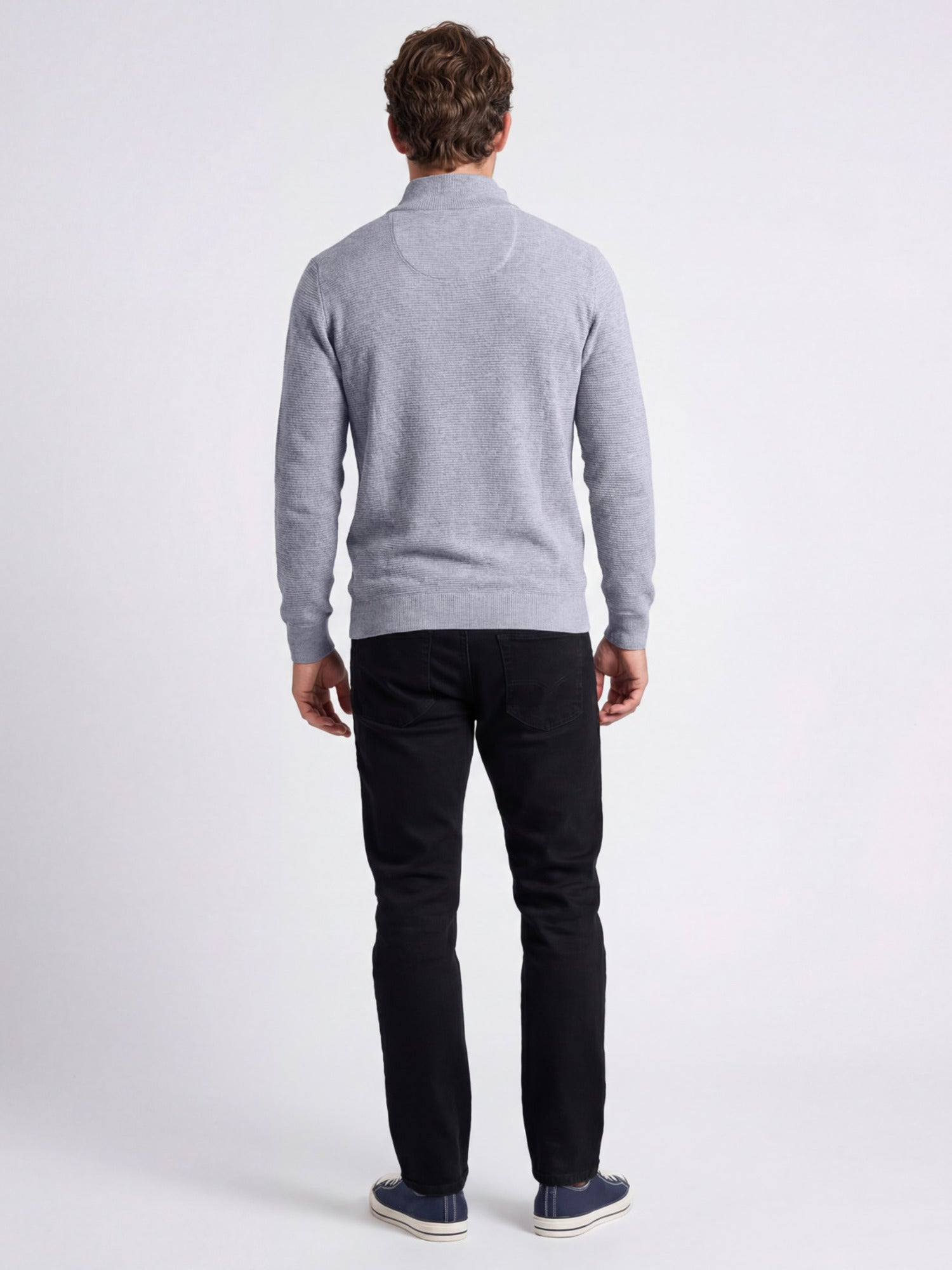 Man wearing a gray sweater and black trousers on a white background