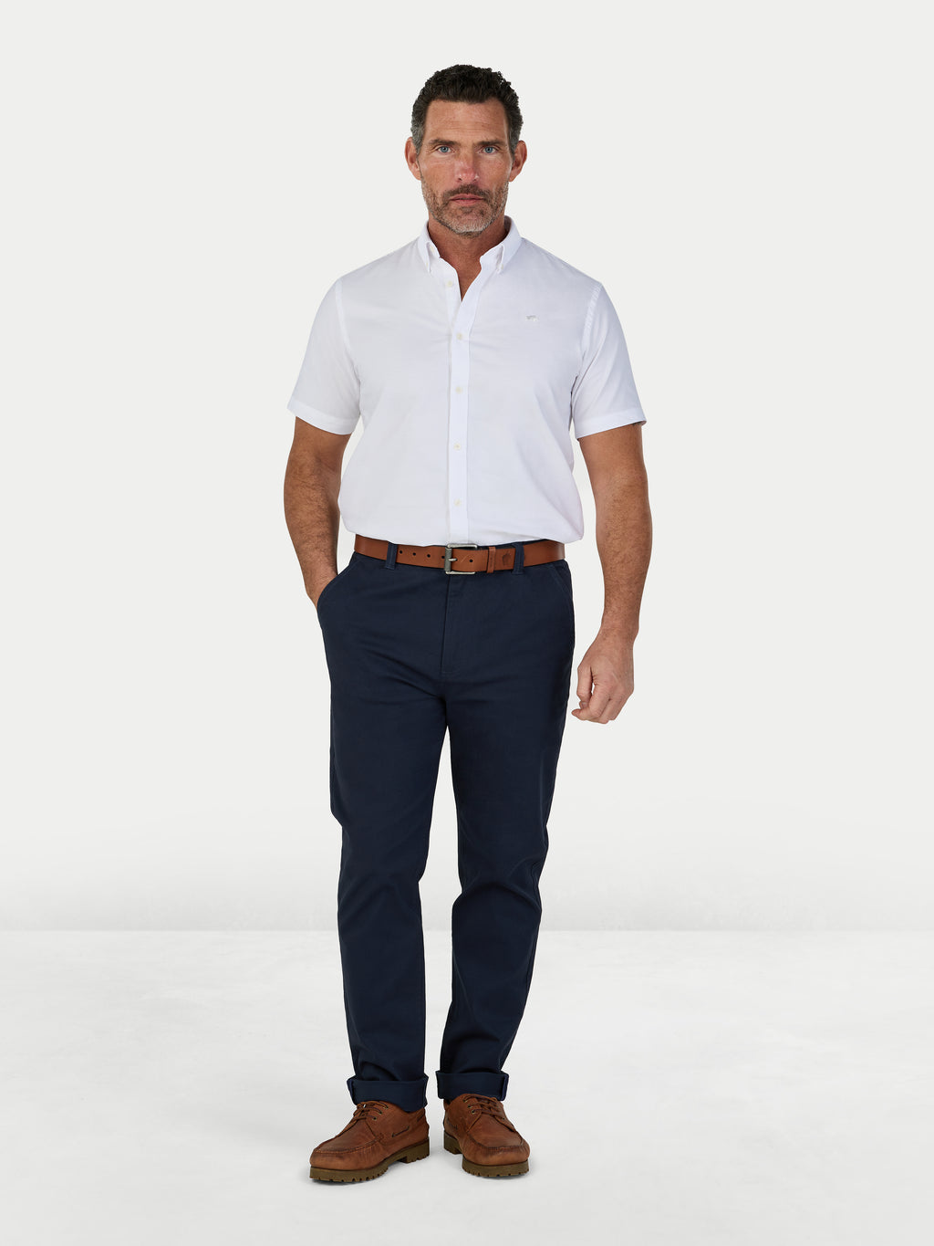 Man wearing a white shirt, navy pants, and brown shoes on a white background