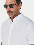 Man wearing a white short-sleeve shirt with a collar against a light background