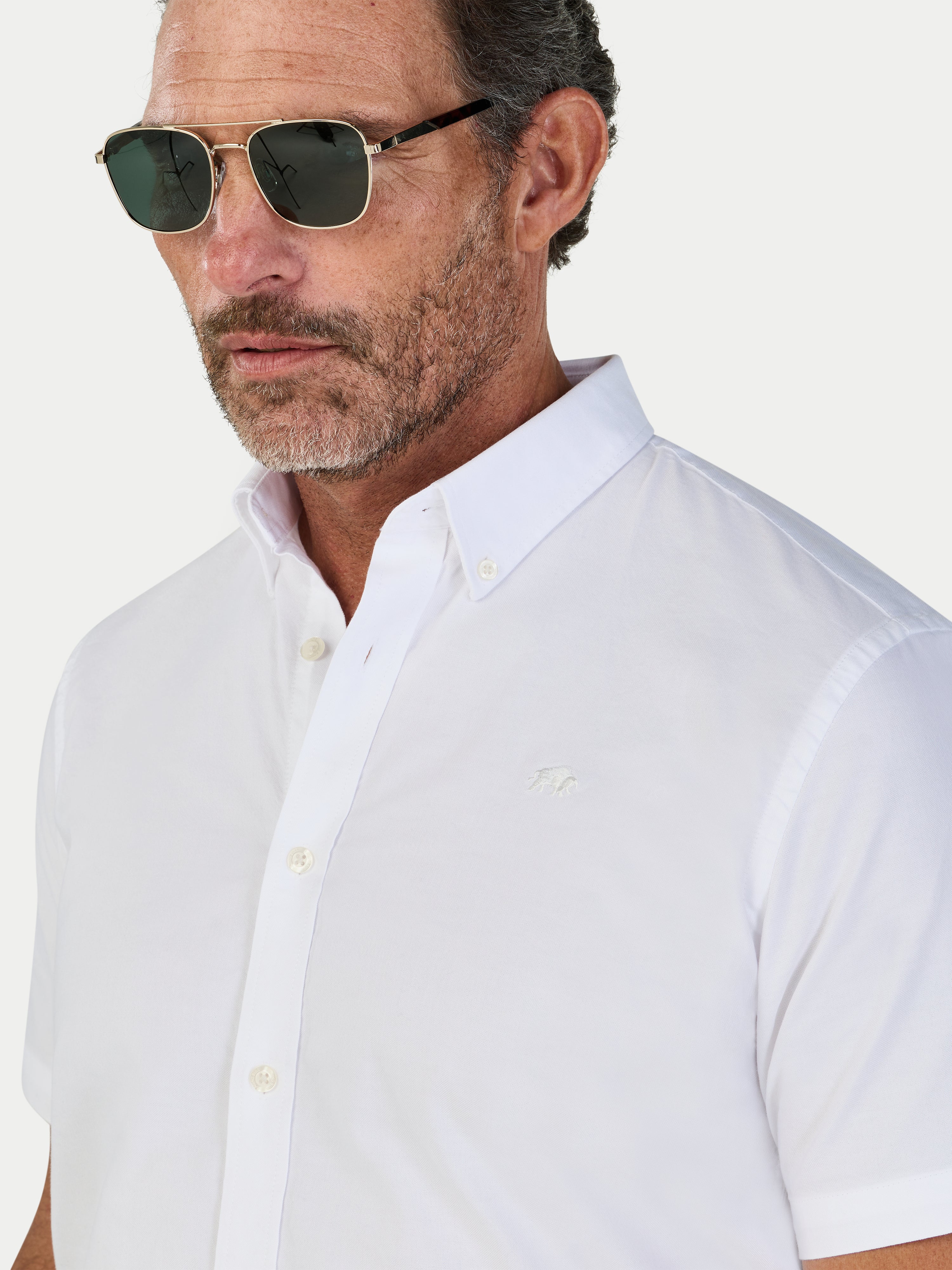 Man wearing a white short-sleeve shirt with a collar against a light background