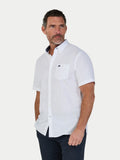 Man wearing a white short-sleeve shirt with a small logo on a light gray background
