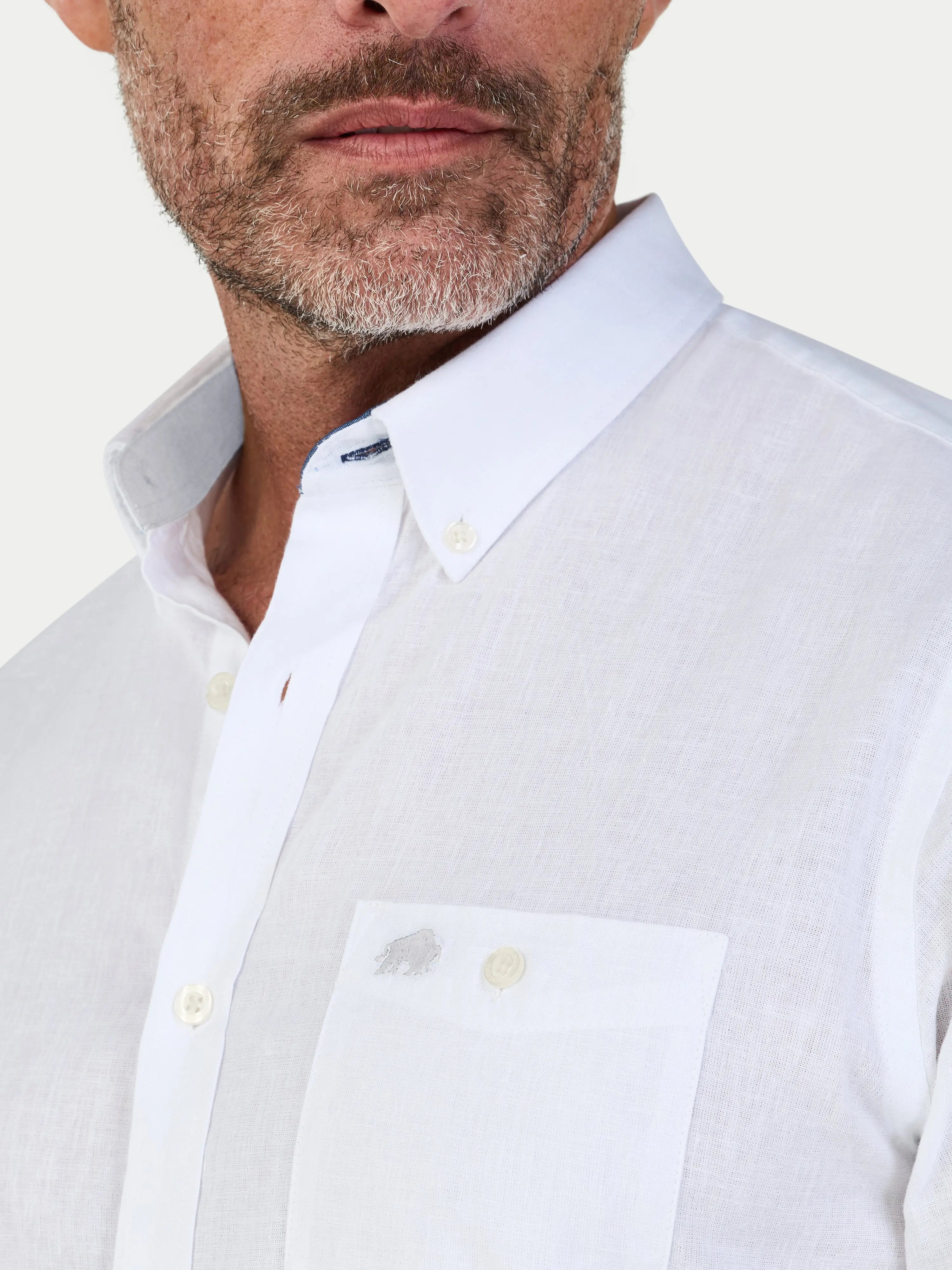 Close-up of a man wearing a Raging Bull short sleeve shirt in white with a pocket on a white background, front detail. 