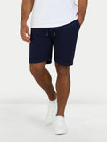 Person wearing navy shorts and white shoes on a white background
