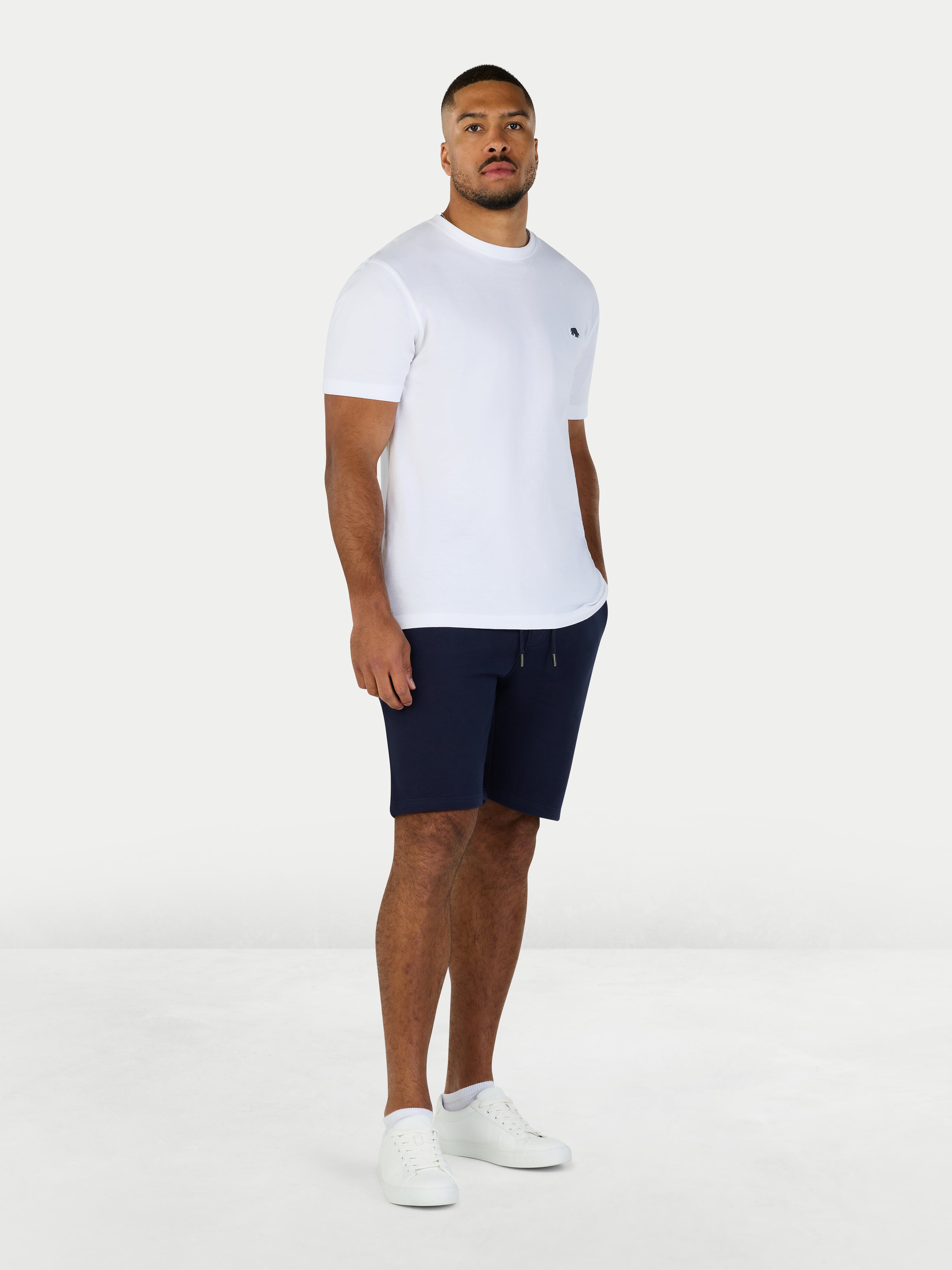 Man wearing a white t-shirt and navy shorts on a white background