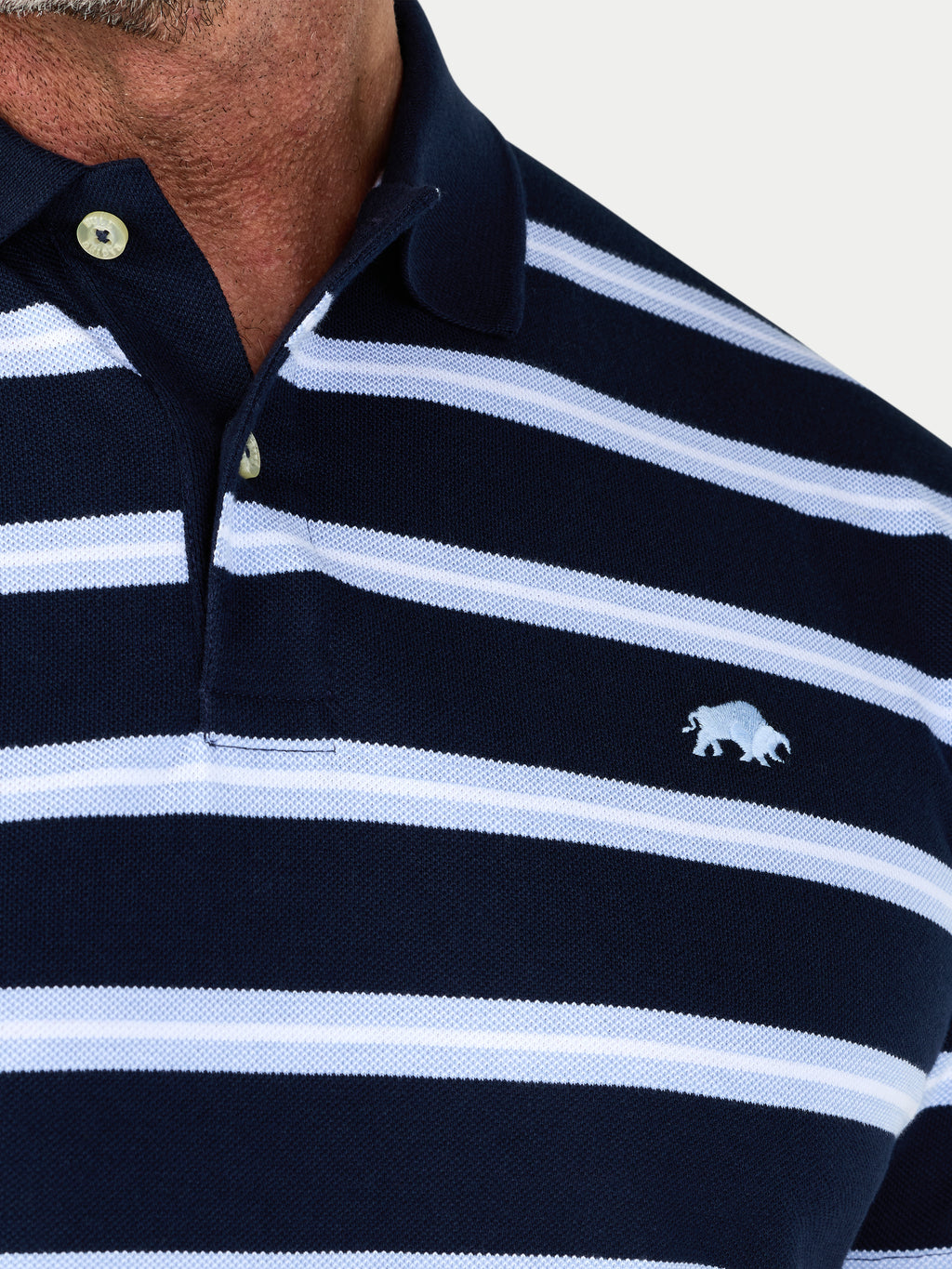 Navy and white striped polo shirt with a logo on a light gray background