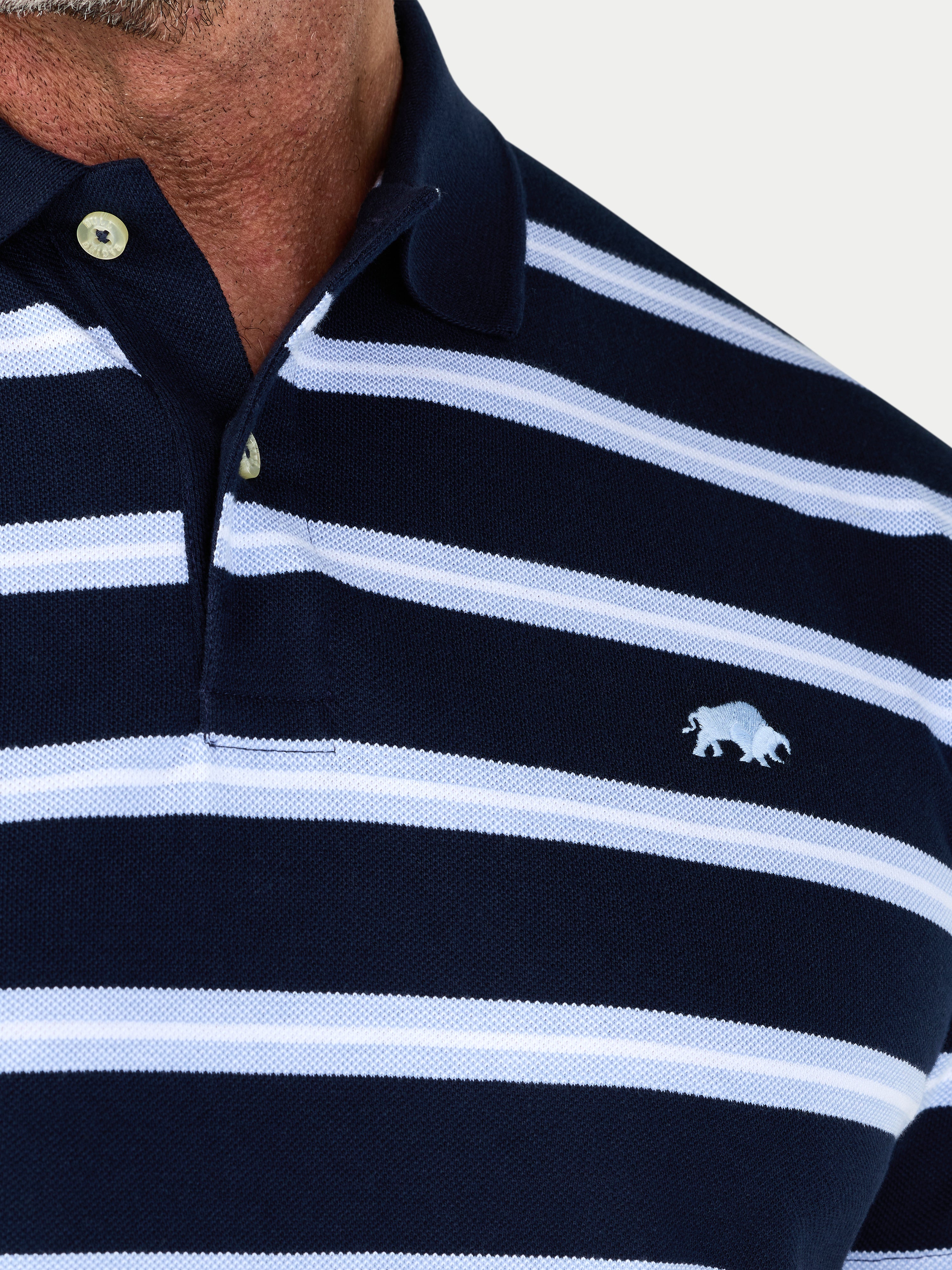 Navy and white striped polo shirt with a logo on a light gray background
