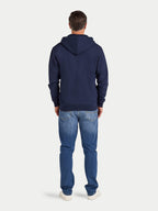 Person wearing a navy hoodie and blue jeans on a white background